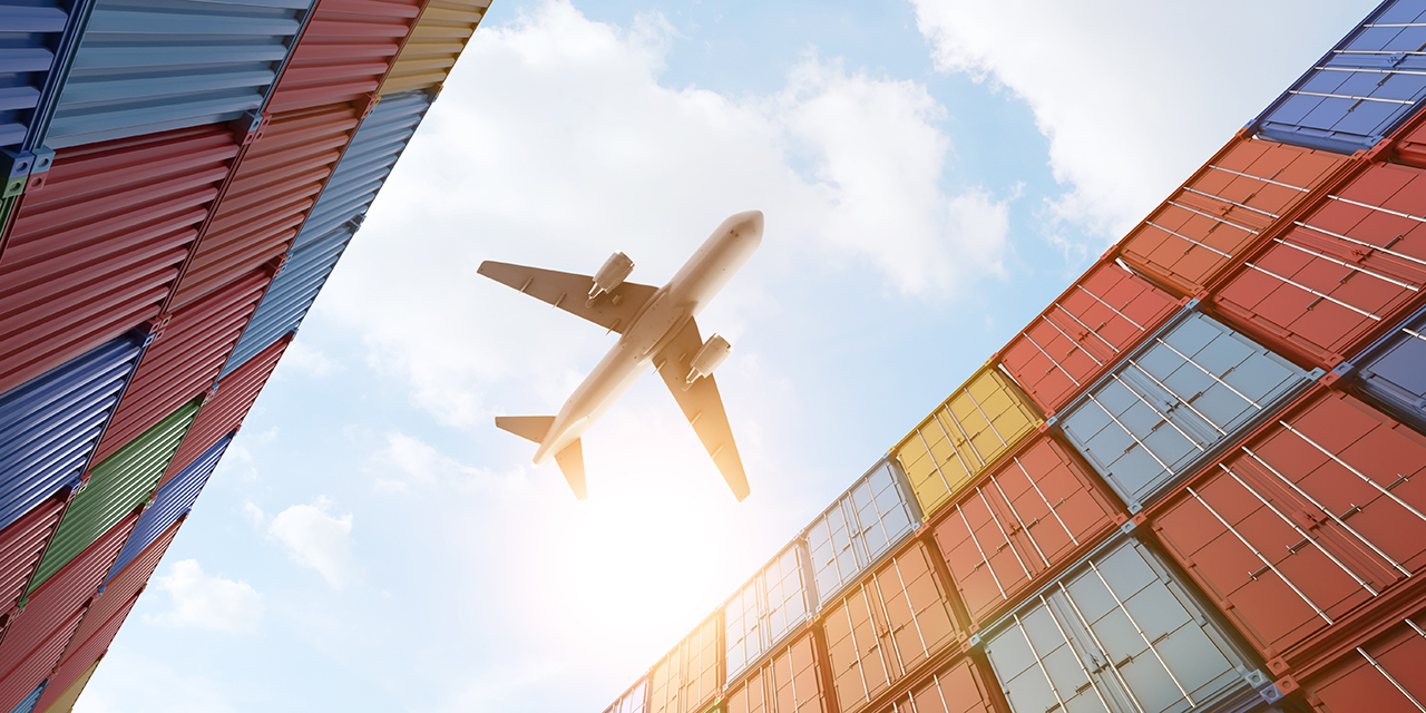 Airplane flying over shipping containers.